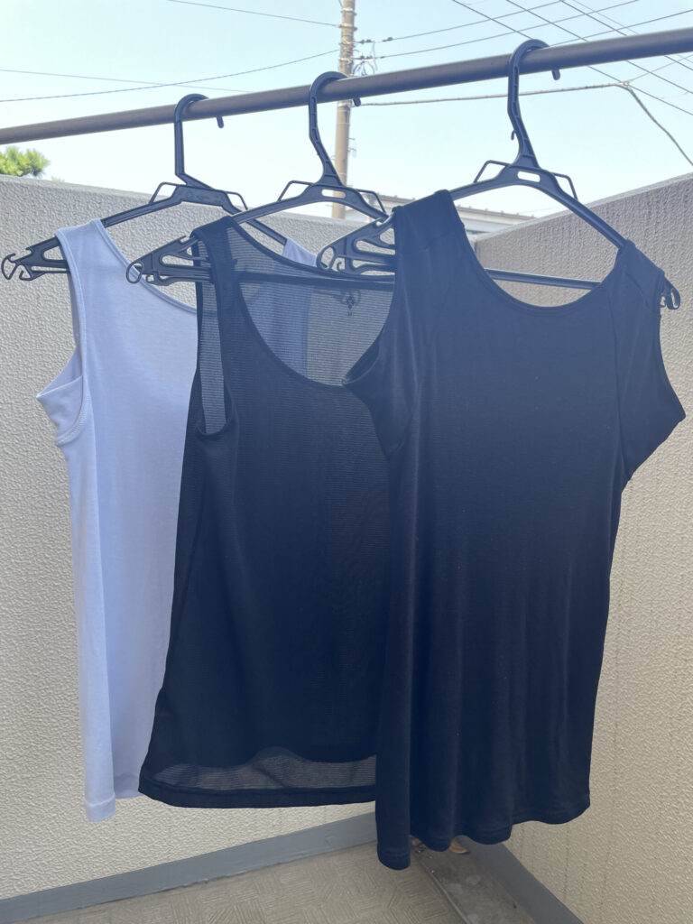 Three tank tops hanging in the shade to dry.